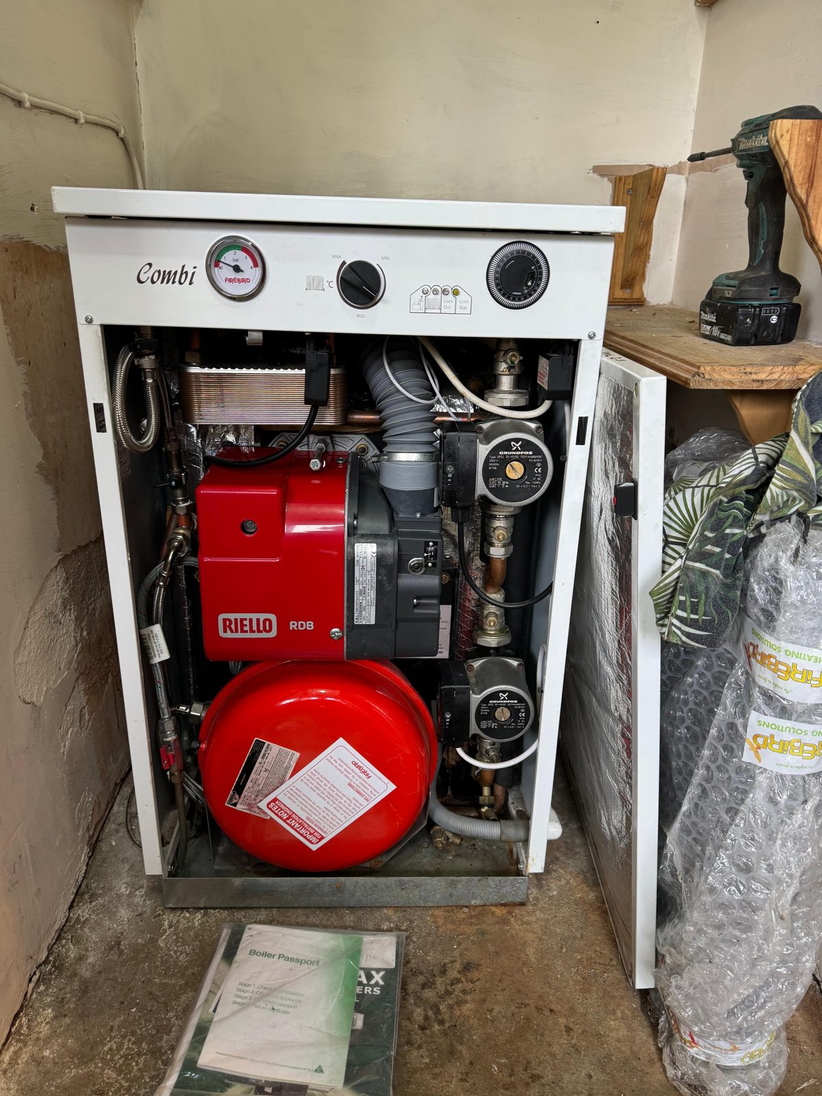A floor-standing oil combi boiler with its front panel open, showing the burner, pumps and expansion vessel